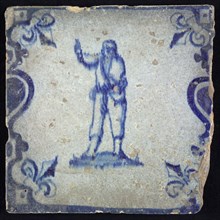 Figure tile, blue with pointing man, between balusters with French lily, wall tile tile sculpture ceramic earthenware glaze