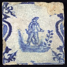 Figure tile, blue with standing man with bat, between balusters with French lily, wall tile tile sculpture ceramic earthenware