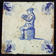 Figure tile, blue with man sitting on barrel with playing cards in hand, corner motif wader, wall tile tile sculpture ceramic