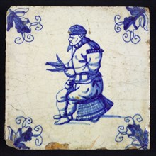 Figure tile, blue with man sitting on basket, cleans fish with knife, Corner motif, wall tile tile sculpture ceramic earthenware