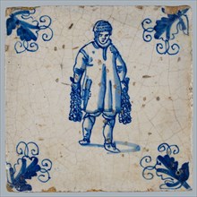 Figure tile, blue with man walking with strings of onions? in both hands, corner motif, vane leaf, wall tile tile sculpture