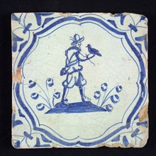 Figure tile, blue with falconer with falcon on the right hand, on the ground, in curly braces with corner motif, wall tile
