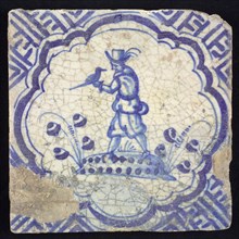 Figure tile, blue with falconer with falcon on the left hand, on ground, in scalloped frame with accolades, corner motif meander