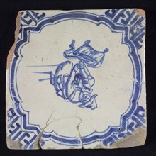 Figure tile, blue with man on knees, hunter taking something out of his bag, scalloped frame with braces, corner motif meander