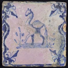 Animal tile, standing dromedary to the left on plot between balusters, in blue on white, corner pattern french lily, baking