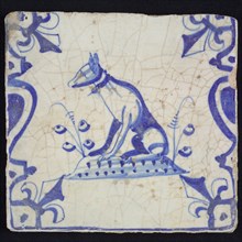 Animal tile, sitting dog to the left on plot between balusters, in blue on white, corner pattern French lily, wall tile