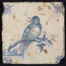 Animal tile, bird on branch looking to the left, blue on white, corner motif ox's head, wall tile tile sculpture ceramic