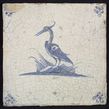Animal tile, standing heron to the left on ground, in blue on white, corner motif spider, wall tile tile sculpture ceramic
