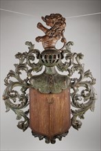 Wooden coat of arms with prong, by Cornelis Westduel, crowned with cage helmet and lion, surrounded by curling motifs, coat of