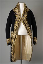 Men's skirt or vest of dark blue cloth with high standing collar and richly embroidered with flowers, vines and borders, statio