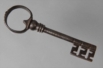 Slightly decorated iron key with heart-shaped eye, hollow key handle, decorated collar and beard with cross-shaped notches, key