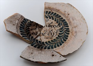 Fragments of faience plate on stand surface, spell-plate, wall plate soil find ceramic earthenware glaze tin glaze, hand-turned