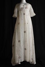 Empire dress of white batiste embroidered with multicolored flower motifs in tambouring, raised waist, short sleeves and wide