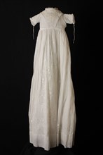 Long flared christening dress of white batiste, V-shaped front and skirt embroidered with fine plumetis, short sleeves