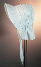 Awning in white cotton, rounded with ruffles and three reinforced legs, wide front and pleated edge in the neck, awning hat