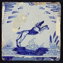 Animal tile, dog jumping over stone or soil in pond, in blue on white, wall tile tile sculpture ceramic earthenware glaze tin