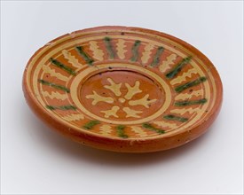 Small earthenware plate with sludge decoration on red background, plate crockery holder soil find ceramic earthenware glaze lead