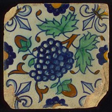 Tile, blue draft, orange, brown and green on white, centrally diagonally placed bunch of grapes, half rosette, corner motif lily