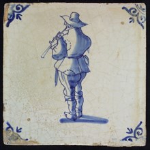 A, Figure tile, blue on white, central flute-playing man, corner pattern ox-head, reverse side marked, wall tile tile sculpture