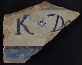Piece of white tile with in blue letters K and De and colored horizontally, tile picture footage fragment ceramics pottery glaze