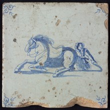 White tile with blue horseman, lying horse, man kneeling behind it; corner pattern ox head, wall tile tile sculpture ceramic
