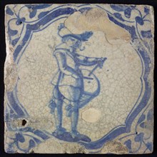 White tile with blue warrior with drum in accolade-shaped frame, corner motif wing leaf, wall tile tile sculpture ceramics