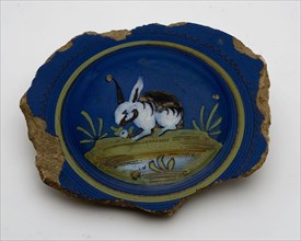 Fragment majolica pancake plate with rabbit or hare on dark blue background, plate crockery holder soil find ceramic earthenware