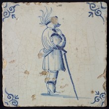 White tile with blue warrior leaning on stick; corner pattern ox head, wall tile tile sculpture ceramic earthenware glaze, baked