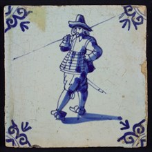 White tile with blue warrior with spear over shoulder; corner pattern ox head, wall tile tile sculpture ceramic earthenware