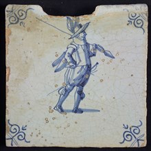 White tile with blue warrior with plume hat and spear and hand in side; corner pattern ox head, wall tile tile sculpture ceramic