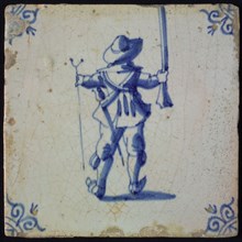 White tile with blue warrior on the back seen with rifle and stand; corner pattern ox head, wall tile tile sculpture ceramic