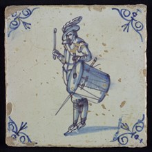 White tile with blue warrior with plume hat, drumming; corner pattern ox head, two shades of blue, wall tile tile sculpture