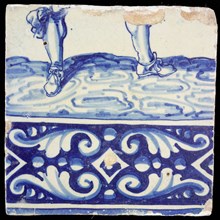 Tile, in blue on white, underneath ornament edge, above it two legs of soldier with shoes and bows, tile picture footage