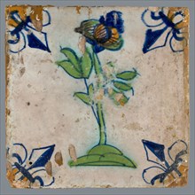 Tile, flower on ground in yellow, green and blue on white, corner pattern french lily, corner point orange, wall tile