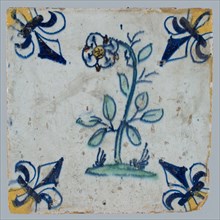 Tile, flower on ground in yellow, brown, green and blue on white, corner pattern french lily, corner point yellow, wall tile
