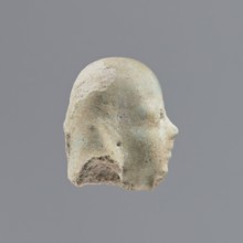 Fragment of a shabti, heads, grave goods, wigs. Head of a shabti figurine with indistinct facial
