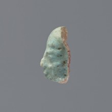 Fragment of a shabti, grave goods, wigs. Face of a shabti figurine with carefully rendered facial