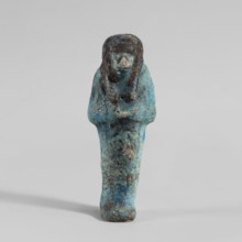Ushabti, Mummy-shaped figurine. Hands folded on the chest—right over left. Hoes in each hand. Large