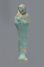Ushabti. Mummy-shaped figurine standing on a base with a flat pillar at the back. Arms folded