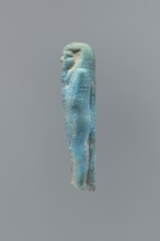 Ushabti, mummy-shaped figurine, back supported on a flat pillar. Feet missing. Arms crossed on the