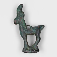 Figurine of an ibex goat standing on a hollow prism base with two pairs of holes on the longer