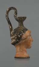Oinochoe in the shape of a woman's head. Yellowish clay with orange surface and areas of shiny