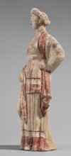 Figurine of a maenad. A young woman standing in a wreath tied with a ribbon is dressed in a chiton