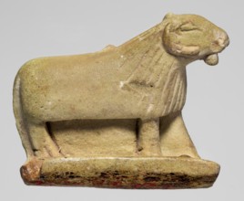 Amulet in the shape of a ram standing on a stand with curled horns and a short beard; the fur