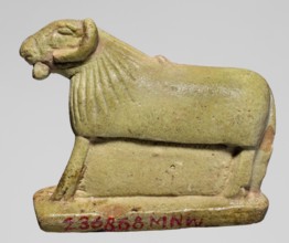 Amulet in the shape of a ram standing on a stand with curled horns and a short beard. The fur