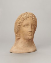 Votive female head, Female head wearing a wreath, from under which lush locks of hair curl down the