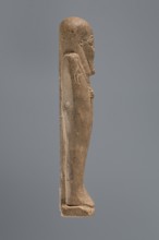 Ushabti, mummy-shaped figurine, standing on a base with a pilaster at the back. Arms crossed on the