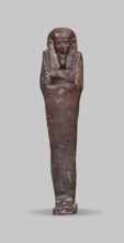 Ushabti, A shabti figurine dressed in a shroud stands on a base. On the head is a smooth wig