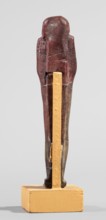 Ushabti, A shabti figurine dressed in a shroud stands on a base. On the head is a smooth wig,