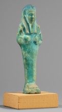 Ushabti; Mummy-shaped funerary figurine standing on a base, supported at the back by a flat